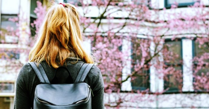 Bambina con zaino in spalla entra in un collegio